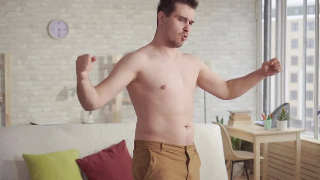 Young man looking in the mirror examines his body.
