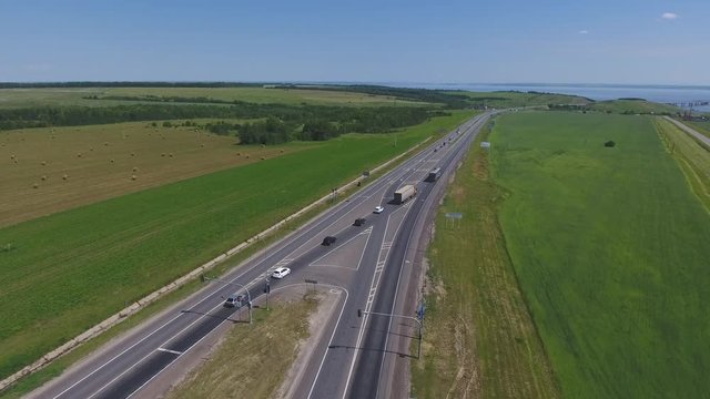The intersection of highways. The movement of cars on the road. Top view of the intersection, cars, field and river. Summer video from the drone. Rural landscape.