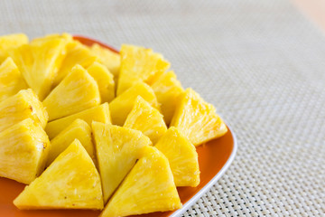 Fototapeta na wymiar Chopped pineapple on a orange color plate