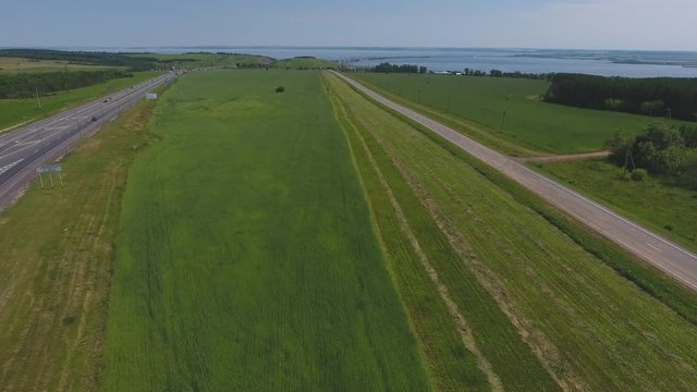 The intersection of highways. The movement of cars on the road. Top view of the intersection, cars, field and river. Summer video from the drone. Rural landscape.