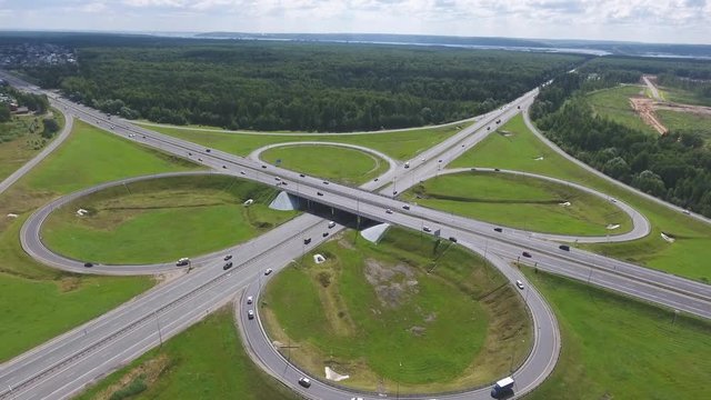 Traffic interchange. Top view of the road, city and forest. Summer video from the drone.