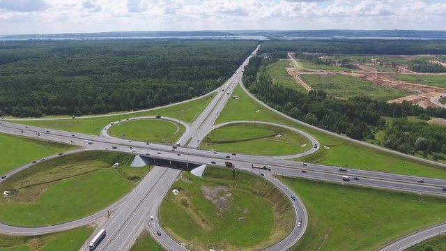 Traffic interchange. Top view of the road, city and forest. Summer video from the drone.