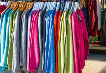 Pullovers hang on a hanger in the store, New Zealand. With selective focus.