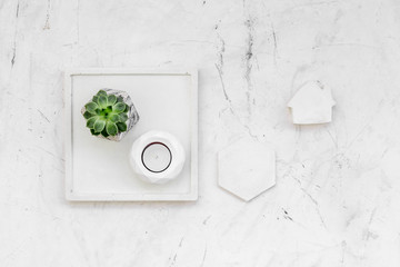 Work desk design with concrete decorations, candle and plant on marble background top view