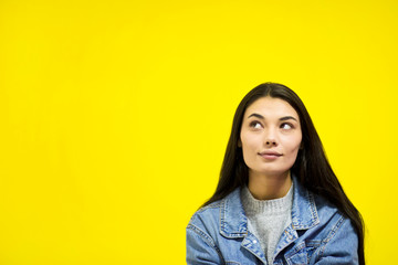 Young beautiful woman looking away at copy space isolated on yellow background.