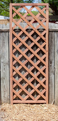 Lattice trellis attached to garden fence in early spring with mulched area below.