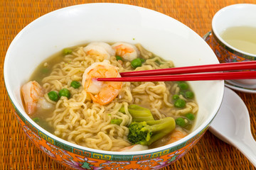 Picking Shrimp from Chinese Noodle Soup with Chopsticks - bamboo mat and Oriental Dishes