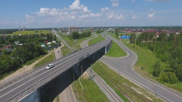 Transport interchange. Movement of cars on the bridge. Crossing the road. Top view of the road, city and forest. Summer video from the drone.