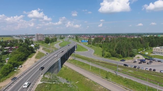 Transport interchange. Movement of cars on the bridge. Crossing the road. Top view of the road, city and forest. Summer video from the drone.
