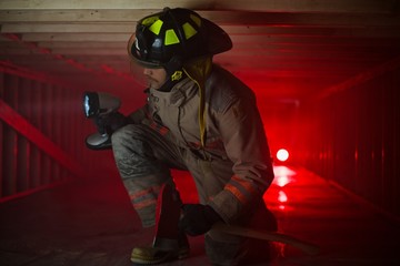 Firefighter in confined spaces looks around with large flashlight