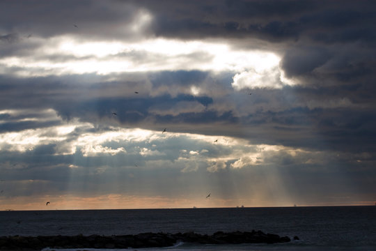 Sunbeams emanating through clouds above the ocean