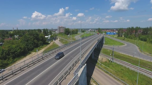 Transport interchange. Movement of cars on the bridge. Crossing the road. Top view of the road, city and forest. Summer video from the drone.