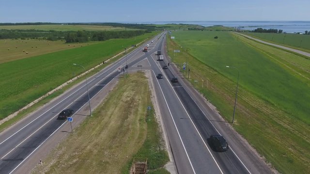 The intersection of highways. The movement of cars on the road. Top view of the intersection, cars, field and river. Summer video from the drone. Rural landscape.