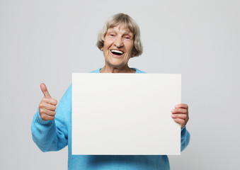 Naklejka premium Aged woman with blank advertising board or copy spacet.