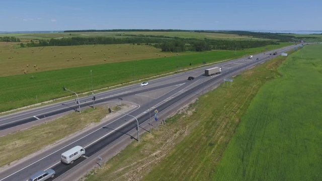 The intersection of highways. The movement of cars on the road. Top view of the intersection, cars, field and river. Summer video from the drone. Rural landscape.
