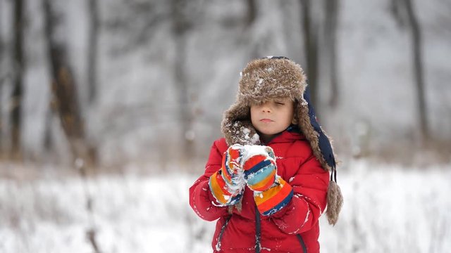 Portrait of funny child with big fur cap and colored gloves eating snow, taste of pure, white  and happy childhood, beautiful winter holiday in nature