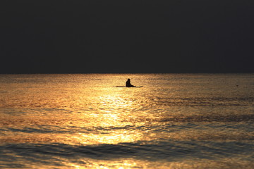 Fototapeta premium Silhouette of Fisherman sitting on his boat in the sunset.