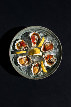 Plate of kumamoto oysters on ice with uni and hot sauce