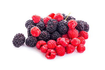 pile of raspberries and blackberries with leaves isolated on white background