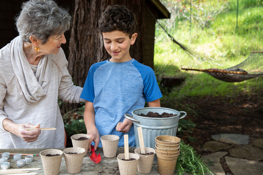 A boy and his grandmother planting seeds in the garden