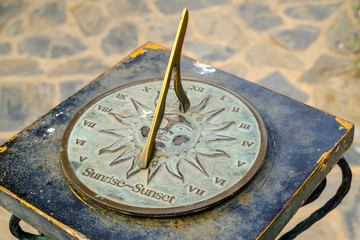 Close-up of a brass sundial mounted on a stone plinth in a garden, Sundial in the Summer sun. - obrazy, fototapety, plakaty