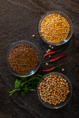 chickpeas lentils and peas in transparent plates on a dark background