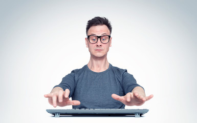 Man in glasses working at the computer, his hands hover over the keyboard while typing. Front view.