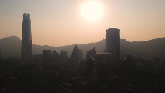 Aerial ascending shot of Santiago skyline against the sun