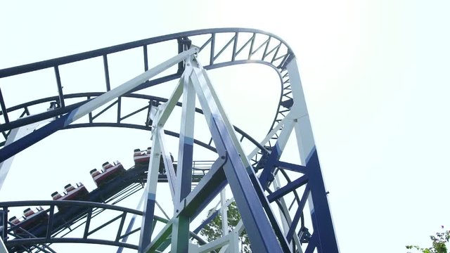 Roller coaster ride working in amusement park. Moving extreme attraction switchback at amusement park. Low angle view.