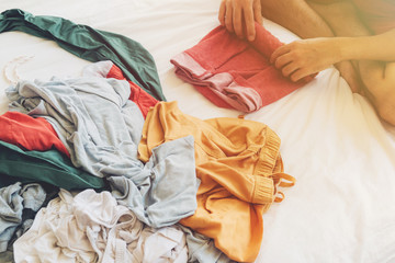 Man is folding and arranging the clothes on the bed.