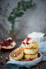 Cheesecakes for Breakfast decorated with pumpkin seeds and pomegranate seeds. Selective focus.