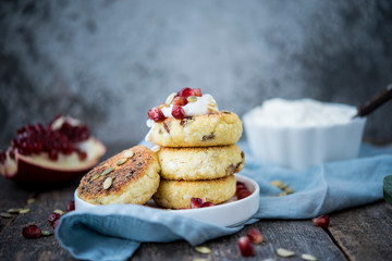 Cheesecakes for Breakfast decorated with pumpkin seeds and pomegranate seeds. Selective focus.