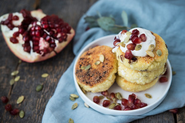Cheesecakes for Breakfast decorated with pumpkin seeds and pomegranate seeds. Selective focus.
