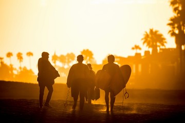 Fototapeta na wymiar silhouette of bodyboarders walking on the beach during sunset