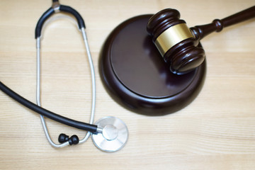 Judges gavel, sounding block and stethoscope on light wooden background, selective focus at sdf. Medical law system, health law, medical jurisprudence and justice concept.