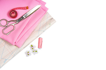 Tailoring. Sewing accessories and accessories for sewing and needlework. Scissors, centimeter, pattern, spool of thread and fabric of pink color on a white background. Isolate, Flat Lay, Copy Space
