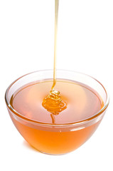 Pouring honey into a glass bowl on a white background