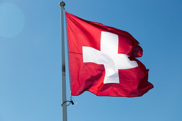 The Flag of Switzerland with a blue sky