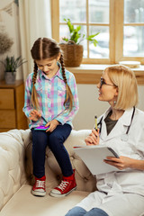 Bewitching pediatrician talking to a girl distracted by phone games