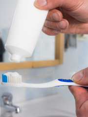 Person putting toothpaste on toothbrush