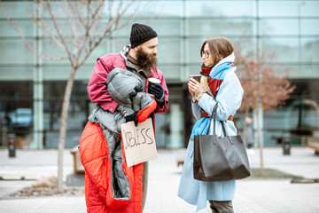 Homeless beggar talking with passing by woman while standing together near the business center....