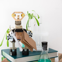 Handmade metal robot in the laboratory. Here are the plants, test tubes, microscope all around....