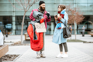 Homeless beggar talking with passing by woman while standing together near the business center....