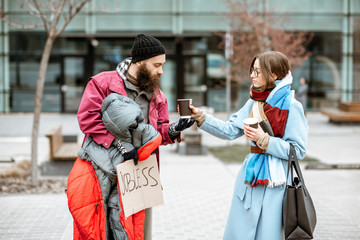 Homeless beggar talking with passing by woman while standing together near the business center. Concept of a human understanding