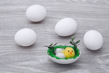 Eggs with chicken on a gray wooden table. Congratulatory card with Easter.