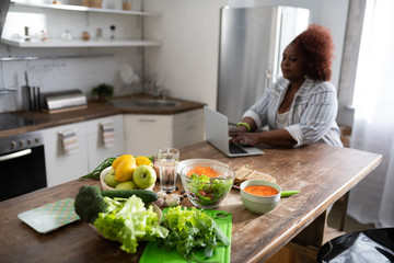 Attentive curly haired woman searching good recipe