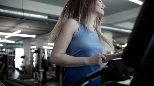 A portrait of young girl or woman doing cardio workout in a gym.