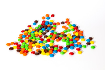 Colorful chocolate M&Ms in and out of focus on white background