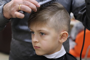 Cute boy model demonstrating hair cut and styling at haidresser'salon