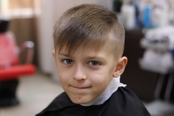 Cute boy model demonstrating hair cut and styling at haidresser'salon